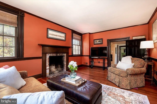 living room featuring a fireplace, crown molding, baseboards, and wood finished floors