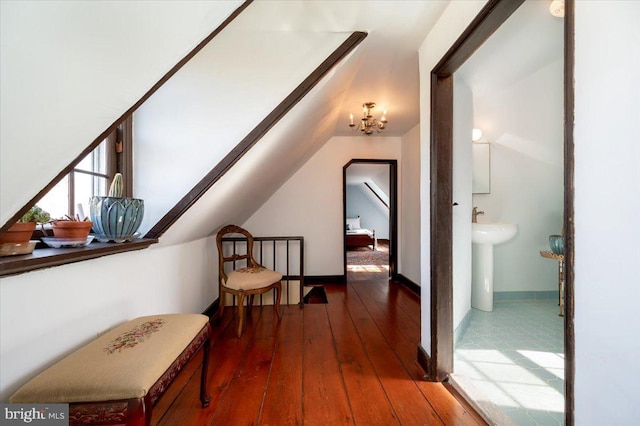 corridor featuring a sink, baseboards, a chandelier, and dark wood-type flooring