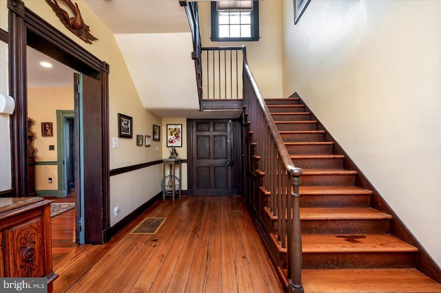 entrance foyer featuring visible vents, stairway, baseboards, and hardwood / wood-style flooring