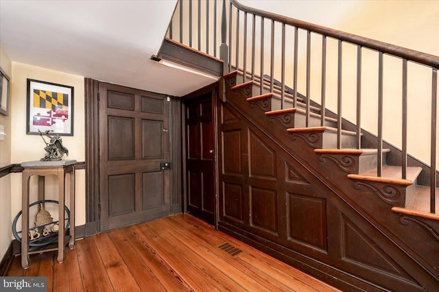 staircase featuring wood-type flooring and visible vents