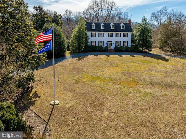 view of front of house featuring a chimney and a front yard