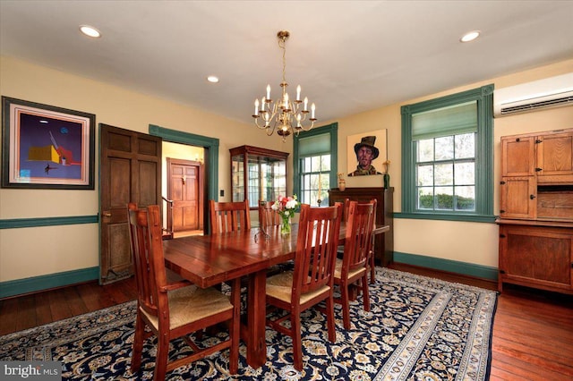 dining room featuring baseboards, a chandelier, hardwood / wood-style floors, and a wall mounted air conditioner