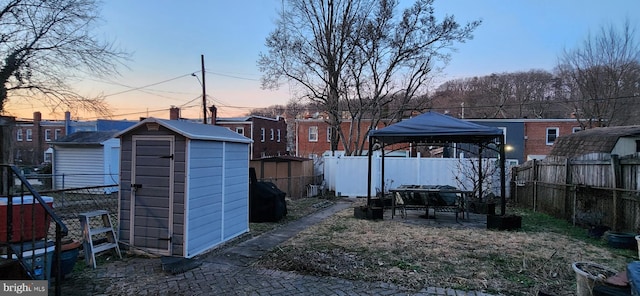 yard at dusk featuring a shed and a gazebo