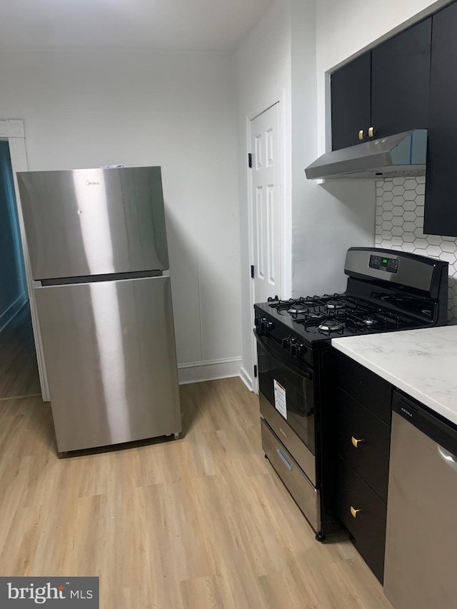 kitchen featuring stainless steel appliances, light hardwood / wood-style floors, and extractor fan