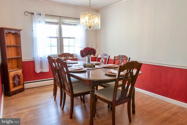 dining space with a wainscoted wall, a baseboard radiator, ornamental molding, wood finished floors, and a chandelier