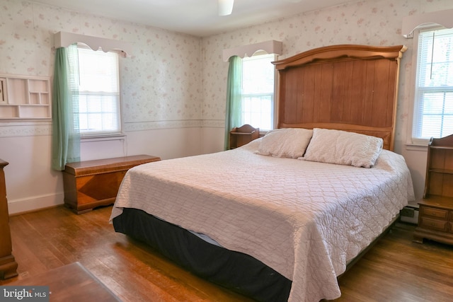 bedroom with wallpapered walls, baseboards, ceiling fan, wood finished floors, and baseboard heating