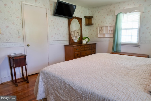 bedroom featuring dark wood-type flooring and wallpapered walls