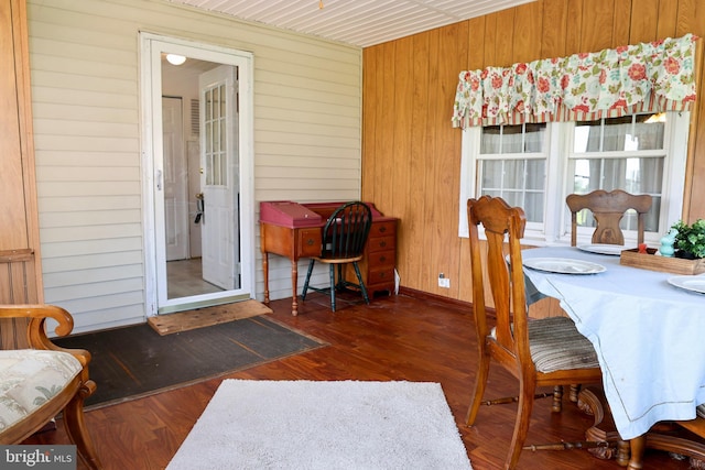 dining room with wood walls and dark wood-style flooring