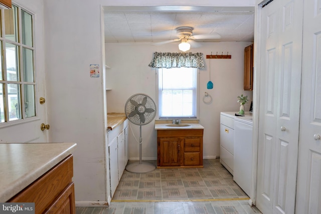 laundry room featuring ceiling fan, separate washer and dryer, a sink, cabinet space, and light floors