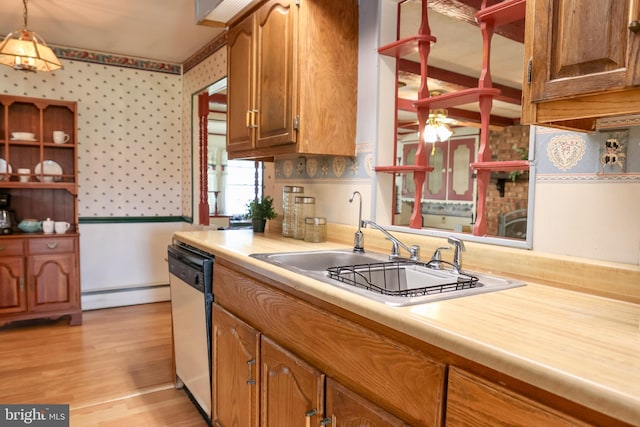 kitchen featuring light countertops, hanging light fixtures, brown cabinetry, dishwasher, and wallpapered walls