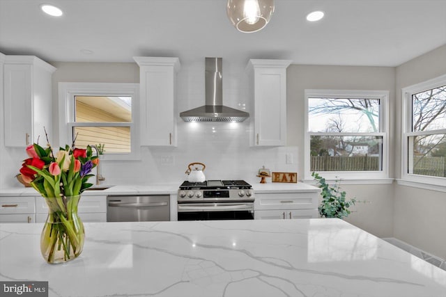 kitchen with white cabinetry, wall chimney exhaust hood, stainless steel appliances, and light stone countertops