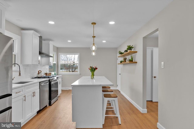 kitchen featuring sink, a center island, pendant lighting, wall chimney range hood, and white cabinets