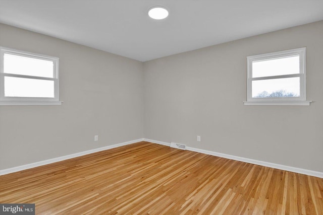 spare room with plenty of natural light and light hardwood / wood-style floors