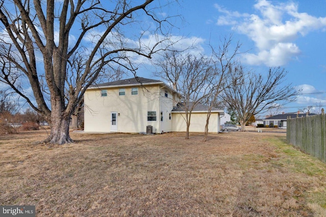 back of house with central AC unit and a yard