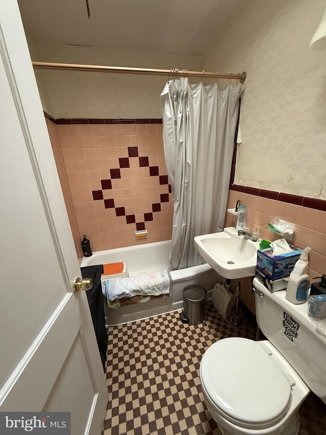 full bathroom featuring toilet, sink, tile walls, and shower / bath combo