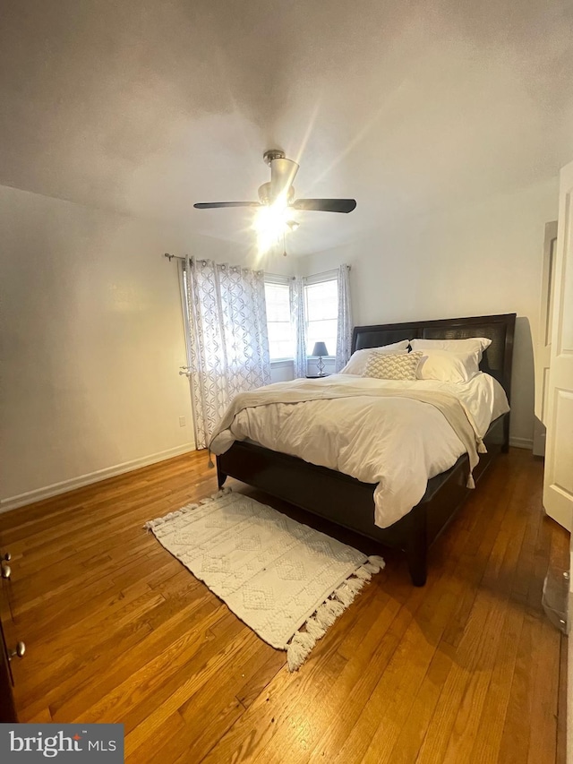 bedroom featuring hardwood / wood-style flooring, a ceiling fan, and baseboards