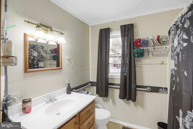 bathroom with tile walls, vanity, crown molding, and toilet