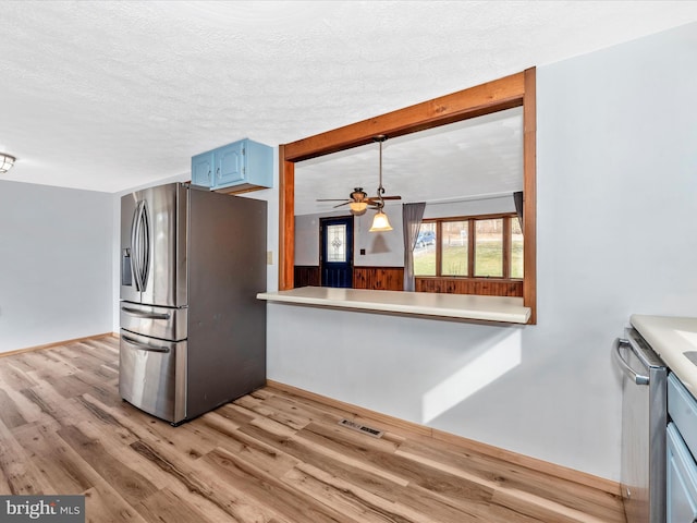 kitchen featuring blue cabinets, a textured ceiling, appliances with stainless steel finishes, ceiling fan, and light hardwood / wood-style floors