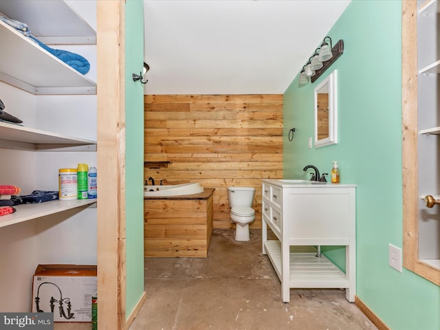 bathroom featuring concrete flooring, vanity, wooden walls, and toilet