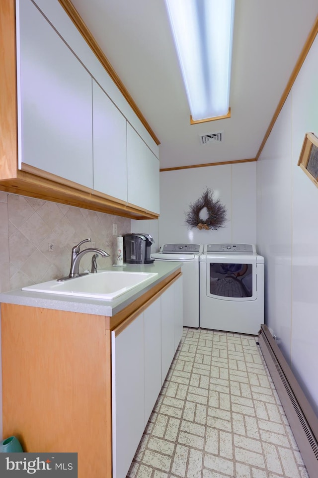 laundry area with washing machine and dryer, cabinets, baseboard heating, sink, and ornamental molding