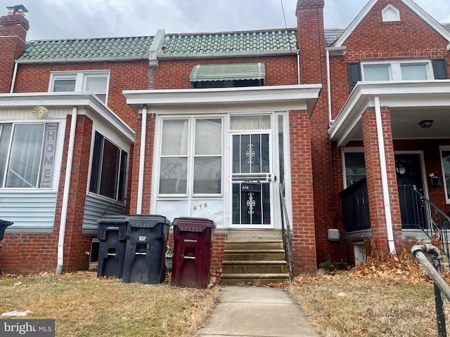 view of front of property with entry steps, brick siding, a tiled roof, and mansard roof