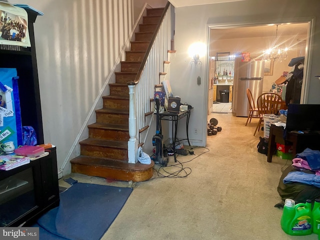 staircase with carpet floors and a chandelier