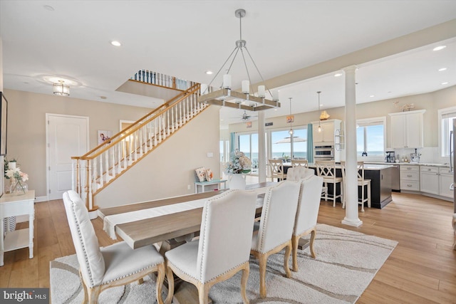 dining area featuring recessed lighting, decorative columns, light wood-style flooring, and stairs