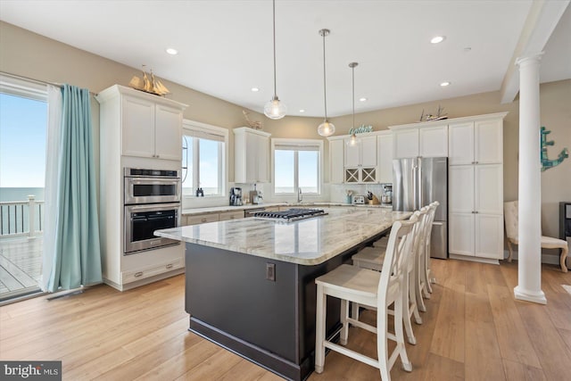 kitchen with stainless steel appliances, a center island, white cabinets, and ornate columns