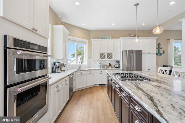 kitchen featuring a wealth of natural light, white cabinets, and appliances with stainless steel finishes