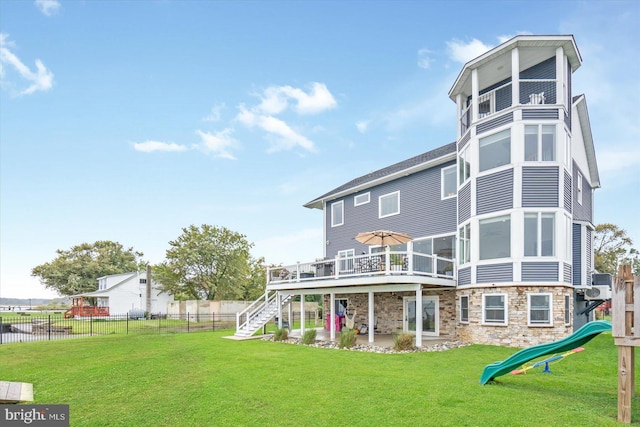 back of property with a playground, fence, stairs, a lawn, and stone siding