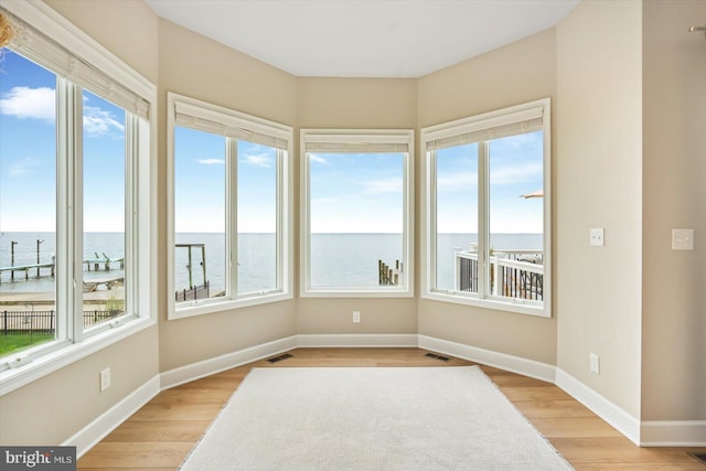 sunroom / solarium with visible vents and a water view