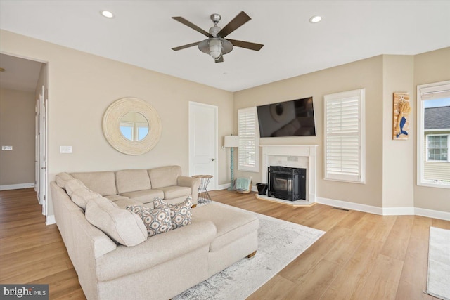 living area with a high end fireplace, recessed lighting, light wood finished floors, baseboards, and ceiling fan