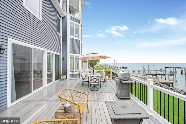 wooden deck with a water view, area for grilling, and a lawn