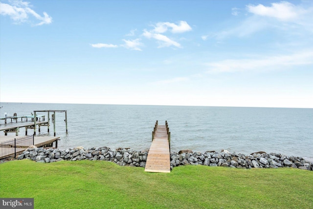 view of dock featuring a water view and a yard