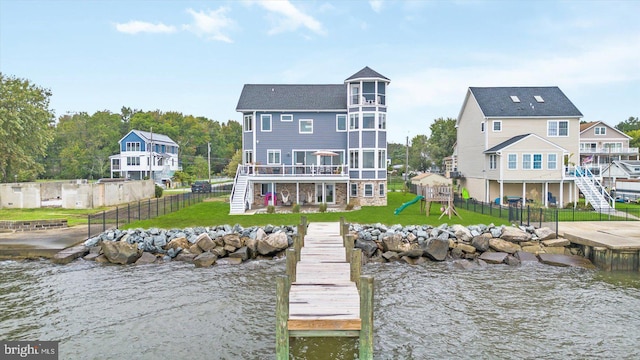 back of property featuring a lawn, fence, a playground, a deck with water view, and stairs