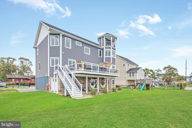 rear view of house featuring a playground, a wooden deck, and a yard