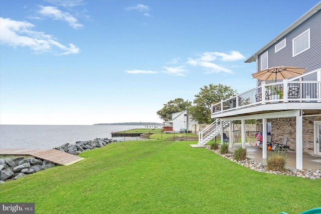 view of yard with a patio area, a deck with water view, stairs, and fence