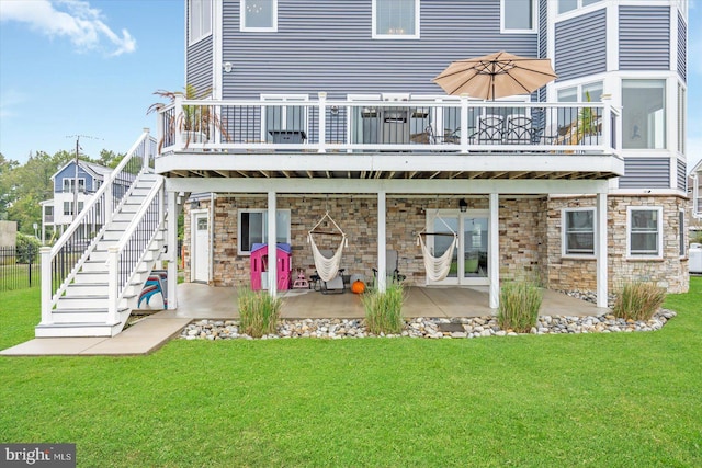 rear view of property featuring a wooden deck, a yard, and a patio area