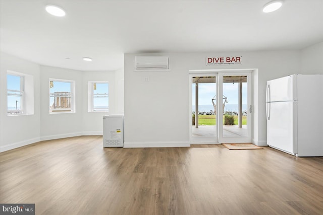 interior space featuring wood finished floors, baseboards, and a wall mounted AC