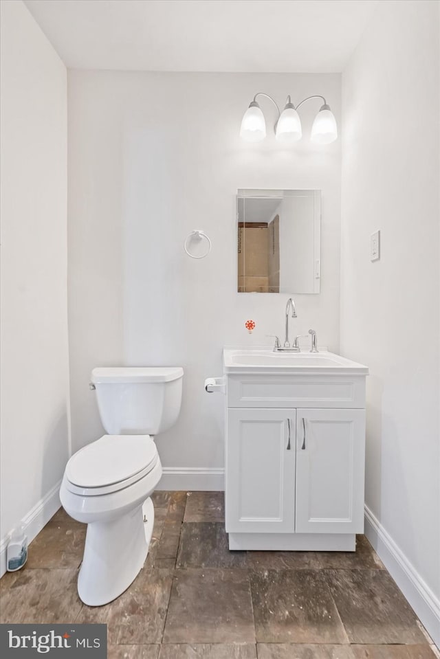 bathroom featuring toilet, vanity, and baseboards