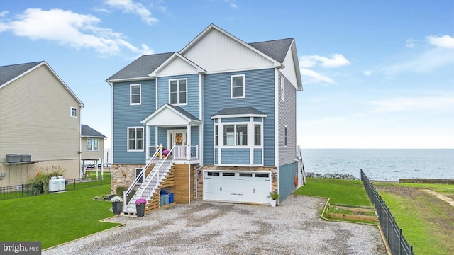 view of front facade with a water view, a garage, and a front lawn