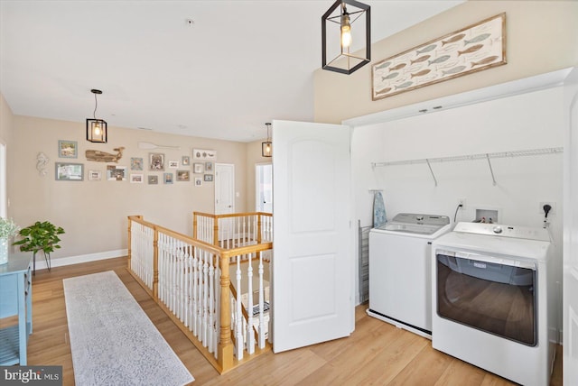 laundry room with light wood-type flooring, baseboards, laundry area, and washing machine and clothes dryer