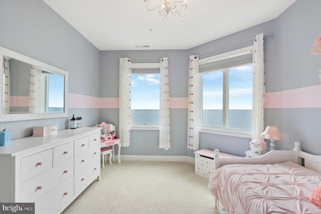 bedroom with a water view, light carpet, and an inviting chandelier