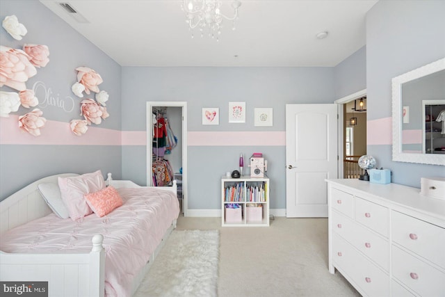 bedroom featuring a walk in closet, light colored carpet, a closet, and a notable chandelier