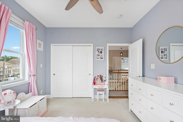 bedroom with a closet, light colored carpet, and a ceiling fan