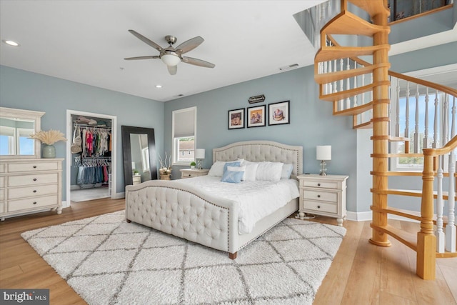 bedroom featuring a walk in closet, light hardwood / wood-style floors, and a closet