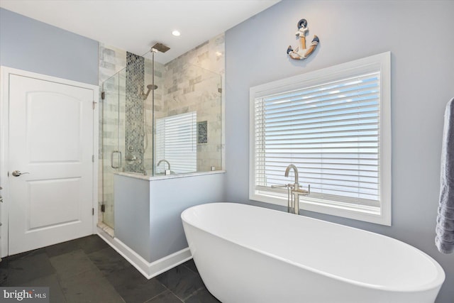 bathroom with a shower stall, a soaking tub, and baseboards