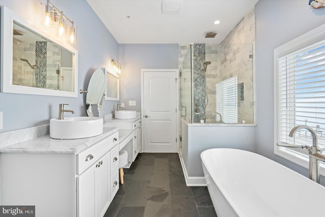 bathroom with double vanity, a freestanding tub, a stall shower, and a sink