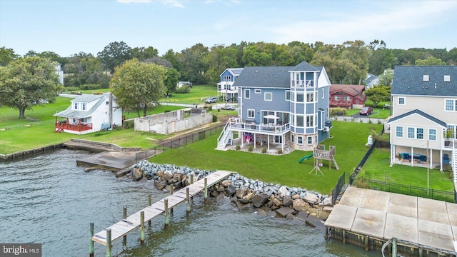 rear view of house featuring an outbuilding, a deck with water view, a yard, stairs, and fence private yard