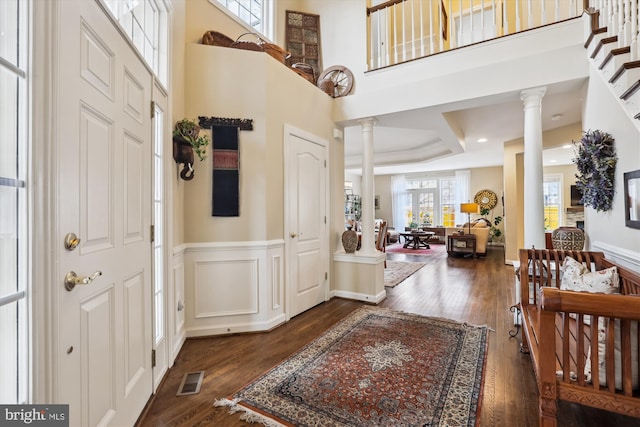 entryway featuring dark wood-style floors, wainscoting, and ornate columns